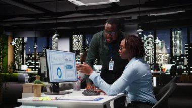 Siyahi iş arkadaşları masaüstü bilgisayarı ile ilgili veri içgörülerini analiz ediyor, şirket faaliyetleri için yeni bir strateji geliştirmeden önce analiz tahminine danışıyorlar. Kamera A.