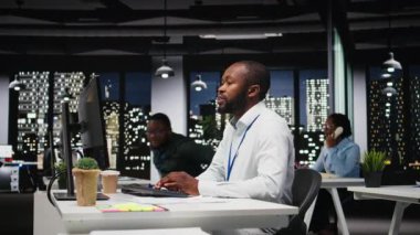 Afrika kökenli Amerikalı çalışanlar aylık raporlar için birbirlerine danışıyorlar, gece geç saatlerde iş verimliliği için KPI verilerini gözden geçiriyorlar. Başarı için çalışanlar arası işbirliği. Kamera A.