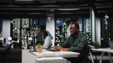 Afrika kökenli Amerikalı danışman geceleri karanlık bir ofiste karmaşık bir soruna odaklanarak masaüstü seçenekleri değerlendiriyor ve öngörüyor. Dikkatli sonuç çıkararak mantıklı bir çözüm arıyorum. Kamera A.