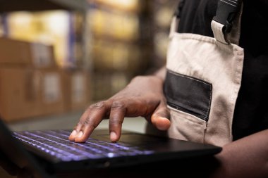 İş kıyafetlerindeki depo çalışanlarını kapatın. Raflardaki kargo paketlerini kontrol edin. Bir dizüstü bilgisayar kullanın..