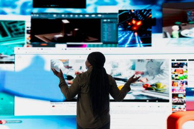 Dijital video duvarına bakan kadın sonsuz eğlence seçiminden faydalanıyor. Çeşitli yayın seçeneklerine erişimin keyfini çıkaran kişi, film ve TV klipleri gösteren ekranlara bakıyor
