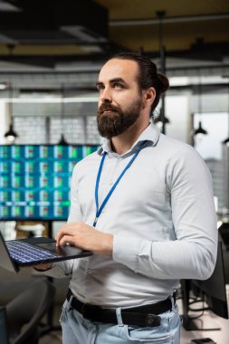 Şirket çalışanı elinde dizüstü bilgisayarla iş analizi yapıyor, verimliliği artırmak için dijital teknolojiyi kullanarak raporları ve çizelgeleri inceliyor. Performans elde etmek için kaynakları hizalayan adam.