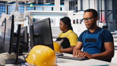 Siyah mühendis güneş paneli montaj yazılımında tanısal kontroller yaparak üretim sürecini ve güneş pillerini alternatif enerji için optimize ediyor. Yüksek teknoloji modern fabrika. Kamera B.