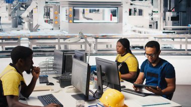 PC ve tabletle parametreleri karşılaştırarak fotovoltaik fabrikasındaki arızalı sistemleri araştıran bir mühendis. Siyahi adam güneş panellerini inceliyor üretim tesisi, yüksek teknoloji. Kamera B.