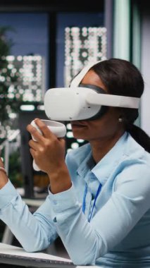 Saatler sonra yapay zeka ile VR kulaklık kullanan dikey video kadın ofis çalışanı, görevlerin tamamlanması ve öngörü tahminleri için sanal gerçeklikle sıkı çalışıyor. 3B simülasyon