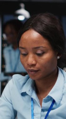 Dikey Siyah Kadın, çalışma saatleri dışında karanlık bir ofiste araştırma ve belgeleme raporları, veri güncellemeleri ve iş girişimleri üzerinde çalışır. Finans hedefleri ve proje geliştirme