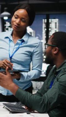 Dikey Video Afrikalı Amerikalı işçiler geceleri görevleri çözmede birbirlerine danışırlar, aylık raporları tamamlarlar ve verimlilik için KPI veri içgörülerini gözden geçirirler. Başarı için işbirliği