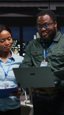 Ortaklar grubunun dikey video portresi gece geç saatlerde cihazlarda veri numaralarını gözden geçiriyor, strateji planlaması ve yeni hedefler için metrik analiz ile iş çözümleri geliştiriyor. Kamera.