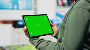 Sınırsız metaevren video içeriğinden zevk alan bir kadın tarafından kullanılan model cihazı. İnternet video kanallarına bakmak için kullanılan yeşil ekran tableti, dijital arkaplan üzerinden izole edilmiş