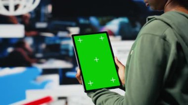 Genç bir kadın tarafından kullanılan yeşil ekran maket tableti. Video yayın hizmetlerinden içerik izliyorlar, boş zamanların tadını çıkarıyorlar. Krom anahtar cihazında VOD yayınlarını eğlendirmeye çalışan genç, kamera B