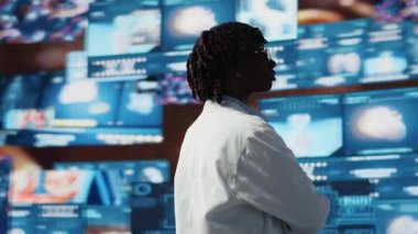 Bilimadamı video taramalarını izliyor. 360 derece dönüşe ayarlı. Laboratuvar önlüğü giyen kadın dijital sağlık panelinin önünde insan anatomisini analiz ederken B kamerasını kapat.