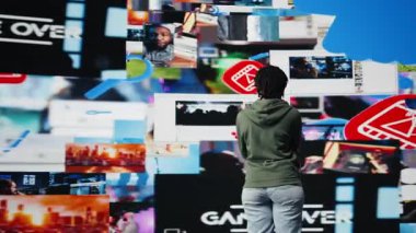 Video klip izleyen, teknolojinin dünya çapında insanları birbirine bağlamasıyla eğlenen biri. Videolara bakmak için dijital arayüz kullanan kadın, dijital çağ yaşam tarzından hoşlanıyor, kamera A