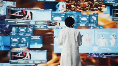 Laboratuvar önlüklü gülümseyen doktor interaktif gösterge panellerini izlerken tıbbi araştırma verilerinden memnun. Multimedya duvarı ve kamera A 'daki tıbbi raporlardan memnun olan mutlu klinisyen.