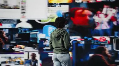 Endüstri uzmanı sosyal medya eğilimleri üzerine sunum yapıyor, videoları video baykuşağında gösteriyor, mikrofonla konuşuyor. Etkilenen kişi, teknoloji zirvesi sunumu sırasında çevrimiçi bağlantının önemini gösteriyor, kamera A