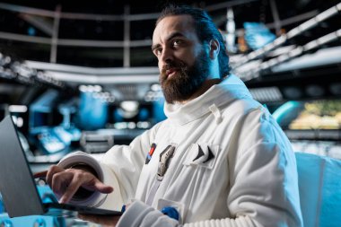 Astronot uzay aracında güneş ölçümlerini gösteren dizüstü bilgisayarı kullanarak galaksi gözlemi yapıyor. Uzay giysisindeki uzay gemisi mürettebatı gezegen keşifleri sırasında dizüstü bilgisayardaki yörüngeye bakıyor.