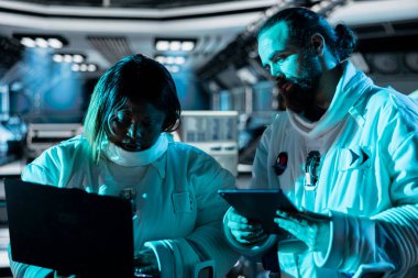 Uzay giysileri giyen astronotlar uzak yabancı bir gezegene yaklaşıyorlar. Mavi ışıkla kaplı uzay adamları uzay yolculuğu işlemleri için hazırlan, aygıtlar üzerindeki verileri oku