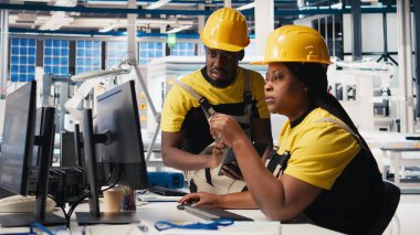 Afrika kökenli Amerikalı işçiler güneş paneli fabrikasındaki imalat ekipmanlarını kontrol ediyor, belge dosyalarını okuyor. Endüstriyel tesisteki mühendisler üretim sürecini inceliyor. Kamera B.