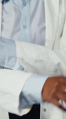 Dikey video Biyomedikal uzmanı laboratuvar önlüğü giyiyor antiviral stratejiler tasarlamak için patojenler üzerinde çalışıyor. Enfeksiyon modellerini ve genomlarını dijital video ile karşılaştıran Afrikalı Amerikalı bir kadın.