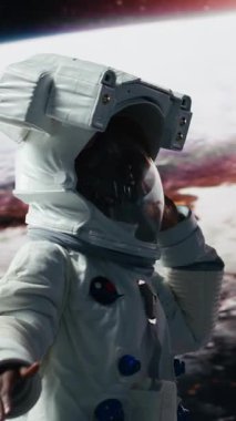 Kozmonot kıyafetli, dans figürleri yapan dikey videolu neşeli kadın gezegensel keşif görevine katılmaktan çok mutlu. Gezegen güzelliği ile heyecanlanan yörünge istasyonu mürettebatı.