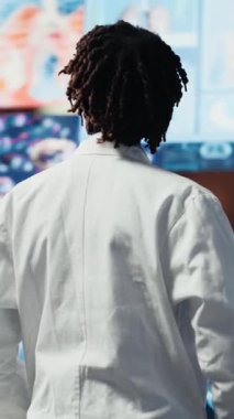 Sağlık araştırmacılarının dikey video portresi fütüristik tıbbi veri görselleştirmelerini analiz ediyor, hastalıkları önlüyor. Bilim adamı yüksek teknolojili hasta taramaları ve kamera kullanarak araştırma geliştirme yapıyor.