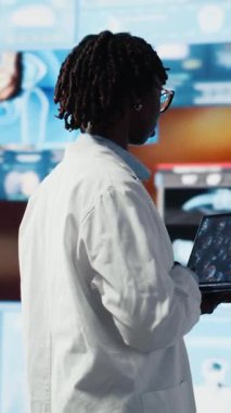 Dikey video bilim kadını dizüstü bilgisayardaki genomlara bakıyor, enfeksiyon modellerini karşılaştırıyor. Afrika kökenli Amerikan biyomedikal mühendisi antiviral stratejiler tasarlamak için dizüstü bilgisayar kullanarak patojenleri inceliyor.