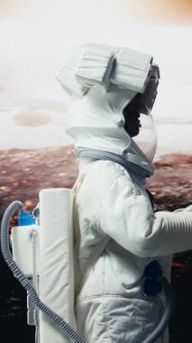 Dikey video gülümseyen astronot uzay gök cismine inmeye hazırlanıyor. Yüksek teknoloji kıyafetli neşeli kozmonot uzay gemisi ile derin uzayı keşfediyor, Mars yüzey araştırması yapıyor, 360 derece dönüyor.