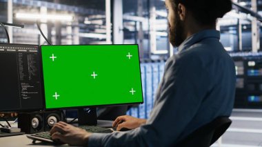 Veri merkezi teknisyeni yeşil ekran model bilgisayar kullanarak yazılım güncellemeleri yapıyor. Sunucu odası bilişim uzmanı, altyapıyı krom anahtar izole ekran PC, kamera A kullanarak optimize ediyor.