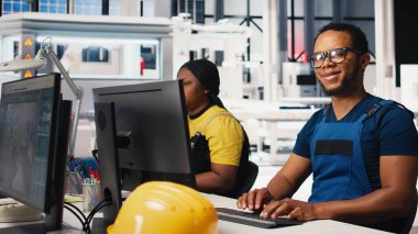 Çalışanlar, yüksek teknolojili sürdürülebilir bir tesiste güneş enerjisi fabrikasında robotik silahları kontrol etmek için bilgisayar kullanıyorlar. Teknisyen otomasyon ayarlarını tutarlı üretimi destekleyecek şekilde ayarlar. Kamera B.