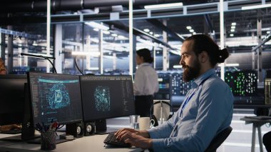 AI LLM görselleştirmesini izlemek için PC kullanan gülümseyen veri merkezi teknisyeni. Sunucu odası çalışanı, yükleme makinelerinin öğrenme süreçlerini denetlemek için bilgisayar kullanıyor. Kamera A