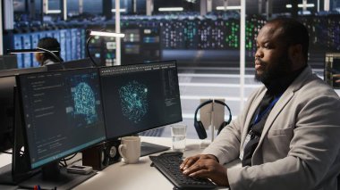 Süper bilgisayar sistemi bakımını bitirdikten sonra neşe içinde dans eden neşeli bir veri merkezi çalışanı. Başarılı yapay zeka model eğitim sonuçlarından çok memnun olan mutlu mühendis sunucu ekipmanlarını denetliyor, kamera A