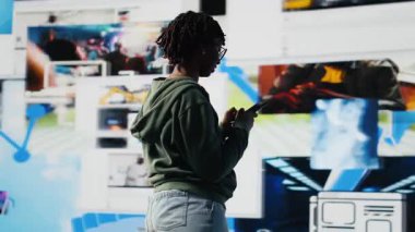 Mutlu kadın arkadaşlarıyla mesajlaşmak, filmleri tartışmak, canlı video duvar kolajının önünde durmak için akıllı telefonu kullanıyor. Diğer sosyal medya kullanıcılarıyla cep telefonu ve kamera B kullanarak sohbet eden gençler