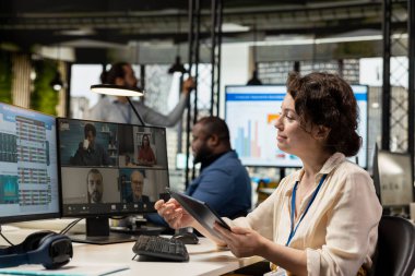 Çalışanlar, çalışma merkezindeki bir web görüntülü konferans görüşmesinde proje brifingini çizelgeler ve raporlarla tartıştılar. Çevrimiçi toplantıya katılan iş ortakları.