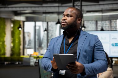 İş yönetimi ve küresel genişleme için verileri ve KPI metriklerini kullanarak, bir tabletle analitik görevleri denetleyen Afrikalı Amerikalı iş adamı. Verimliliği ve verimliliği arttır.