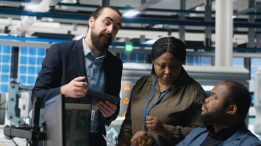 Çok ırklı usta mühendisler güneş panelleri üretimi için yüksek teknoloji üretim hattı üzerinde takım çalışması yapıyorlar. Etkinlik üretimi, teknik içgörü ve yeşil enerji için işbirliği birleştiriyorlar. Kamera B.