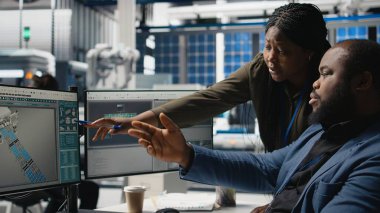 Siyahi mühendisler teknisyenleri bir güneş paneli fabrikasında fikirlerini paylaşıyor, projeleri gözden geçiriyor ve yenilenebilir enerji üretimini ve sürdürülebilir yeniliği geliştirmek için fikirlerini paylaşıyor. Kamera A.