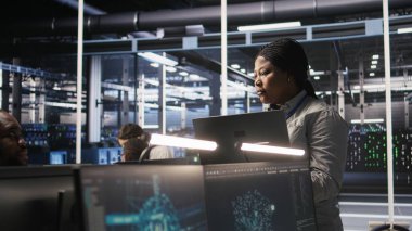 Veri Merkezi yöneticisi denetleme mühendisi bilgisayar çalışma istasyonundaki sinirsel ağları analiz etmek için yazılım geliştiriyor. Ekip lideri ve çalışan gözlemleme sistemi AI sunucu odasında, kamera A