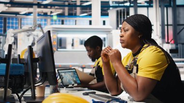 Güneş paneli mühendisi, elektrik santralindeki yüksek teknoloji üretim ekipmanlarını kullanarak, sistem tasarımlarını masaüstü bilgisayarında gözden geçiriyor. Teknisyen fotovoltaik teknolojiyi optimize etmeye çalışıyor. Kamera B.