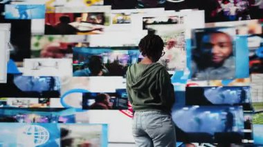 İnternete göz atmak için cep telefonu kullanan neşeli genç bir kadın. Etrafı videolarla çevrili. Gülümseyen Afrikalı Amerikalı ergen boş zamanlarını akıllı telefondan ve kamera A 'dan online videoları izleyerek geçiriyor.