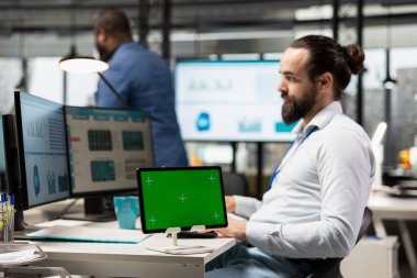 Şirket uzmanı tablet üzerindeki çizelgeleri analiz etmek, iş yönetimi verimliliğini artırmak ve büyüme hedeflerine ulaşmak için strateji raporları hazırlamak için pc monitörü kullanır..