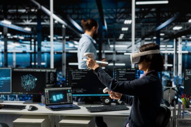 Veri merkezi teknisyeni sanal gerçeklik kullanarak yapay zeka sistemlerini izliyor, derin öğrenme parametrelerini ayarlıyor. VR kulaklık takan sunucu odası bilişim uzmanı sinirsel ağların performansını artırıyor