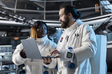 Uzay gemisinde seyahat eden araştırmacılar yörüngede dizüstü bilgisayar kullanarak bilimsel deneyler yapıyorlar. Bilim adamları kozmik yolculuk sırasında deneysel gözlemleri belgelemek için dizüstü bilgisayar kullanıyorlar.