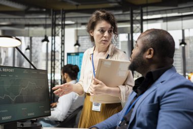 Şirket ofisindeki proje brifingleriyle ilgilenen çeşitli çalışma ekipleri, kaynak tahsisi için çizelge ve performans ölçümlerini birlikte analiz ederler. Hedeflere ulaşılması için strateji optimize ediliyor.