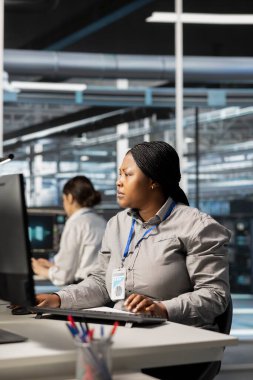 Veri merkezi yazılım geliştiricisi, altyapıyı inceleyerek, tanısal betikler çalıştırıyor. Afrika kökenli Amerikan sunucu odası bilişim uzmanı performans ölçümlerini değerlendirmek ve sistem istikrarını korumak için PC kullanıyor