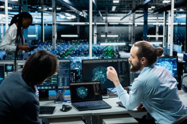 Veri merkezindeki bir grup programcı yapay zeka teknolojisinin yardımıyla yükseltilmiş sunucu rafları kuruyor. Sunucu odası çalışanları konuşuyor, yapay zeka kullanarak şirket ağlarını geliştiriyorlar.