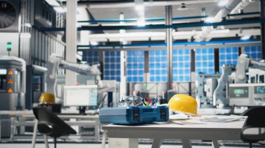 Robotları iş başında gösteren yüksek teknoloji imalat ortamı, fotovoltaik sistem izleme ve masada gerekli güvenlik ekipmanları. Modern yenilenebilir enerji üretim hattı.