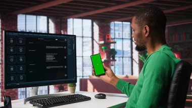 Siyah adam bilgisayar ekranının yanındaki akıllı yapay zeka sohbet robotuyla iletişim kuruyor, akıllı yenilikçi sistem kullanıyor. Makine öğrenimi gelişmiş algoritmalar aracılığıyla verimliliği artırır. Kamera B.