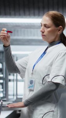 Dikey video kadın doktor klinik deney sırasında hastadan alınan kan örneklerini kontrol ediyor, hayati değerleri, dozaj reaksiyonlarını ve tedavi sürecini izliyor. Kadın ileri düzey sağlık bilimleri üzerine çalışıyor. Kamera B.