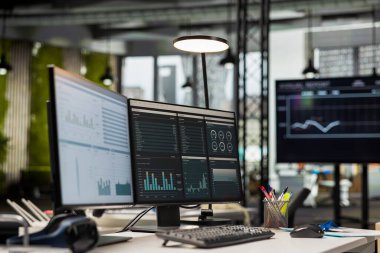 Boş şirket ofisinde modern teknoloji ve çift monitörler, iş stratejisi için hazır analitik araçlar ve profesyonel büyüme ve örgütsel başarıyı desteklemek için rapor yazma.