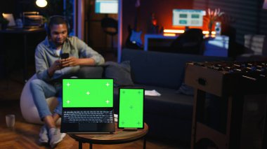 Afro-Amerikalı bir adam cep telefonunun yanındaki fotokopi makinesinin yanında rahatlarken kendini tatmin olmuş ve rahat hissediyor. Salondaki serbest çalışan uzaktan kumandayla kendini mutlu hissediyor. Kamera A.