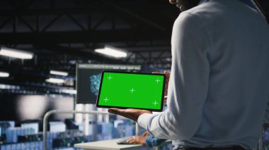 Nöro ağ çıktılarını analiz etmek için krom anahtar aygıt kullanan bilişim uzmanlarını kapatın. Veri merkezi yönetimi, bulanık arkaplanda yapay zeka görsellemesini inceleyen meslektaşının yanında yeşil ekran tableti kullanır